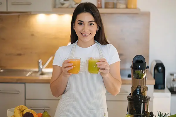 Eine Frau hält zwei Gläser mit frischgepresstem Gemüsesaft hoch